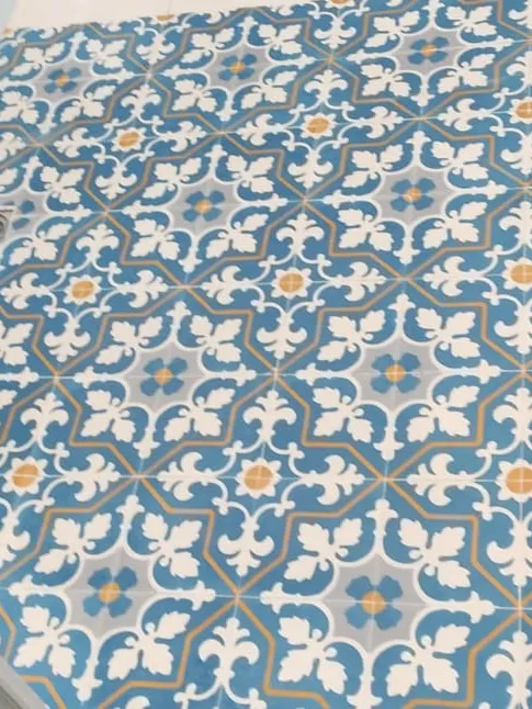 A repeating blue floral pattern across a cement tile floor