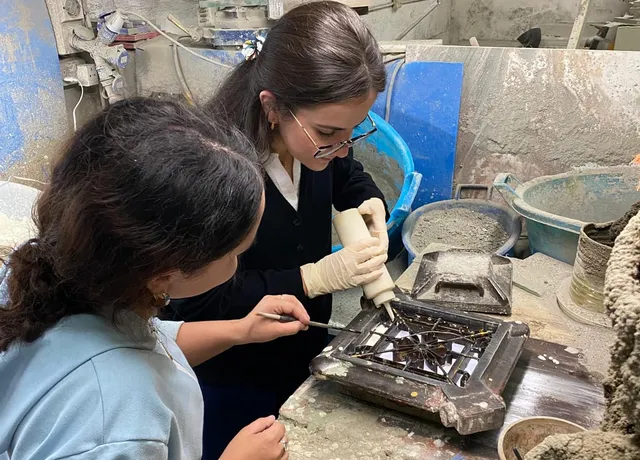 A participant concentrating over a mould at the bench